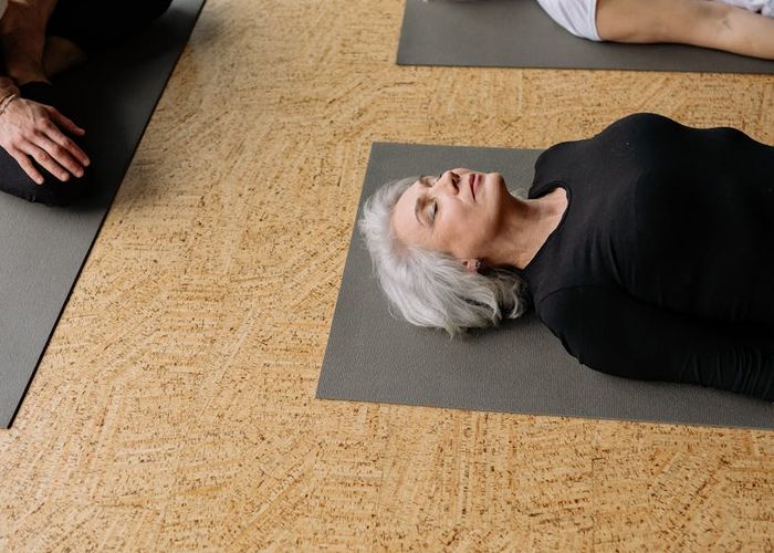 Person performing a balanced yoga sequence in a dark studio.